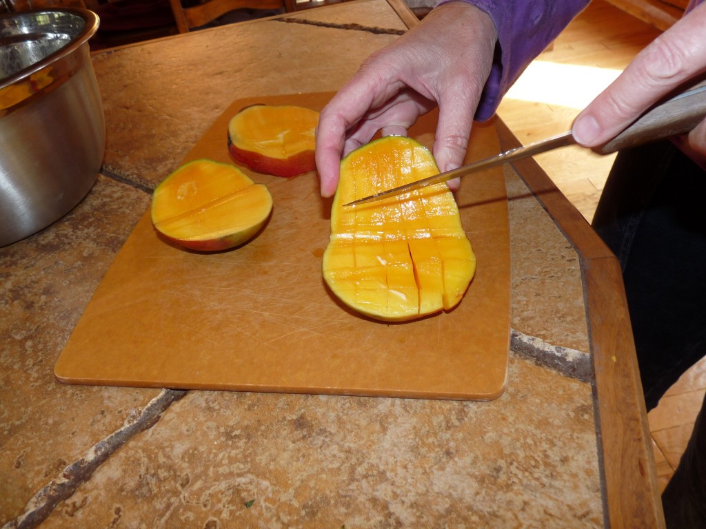Slice mango on each side as close to the pit as possible. Then dice the mango by slicing vertically and horizontally, being careful to not cut through the skin.